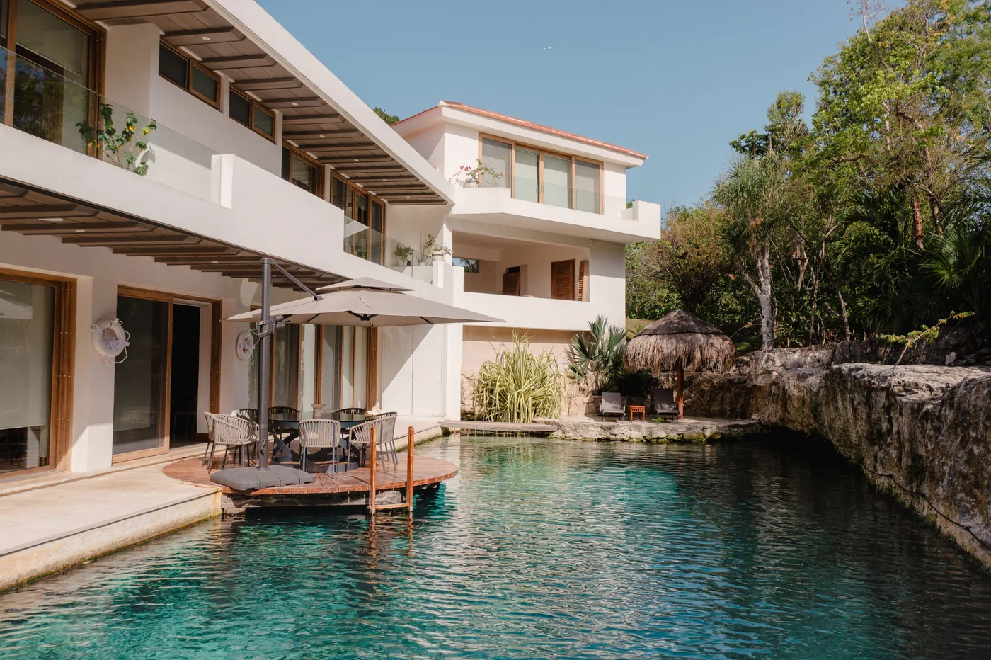 The pool and cenote at Casa Piedra de Agua, with the villa's shaded terrace and dining deck beside the jungle